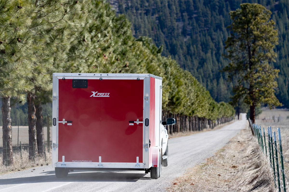 Back View Of White Truck Hauling Xpress White Enclosed Cargo 8.5 Wide Trailer