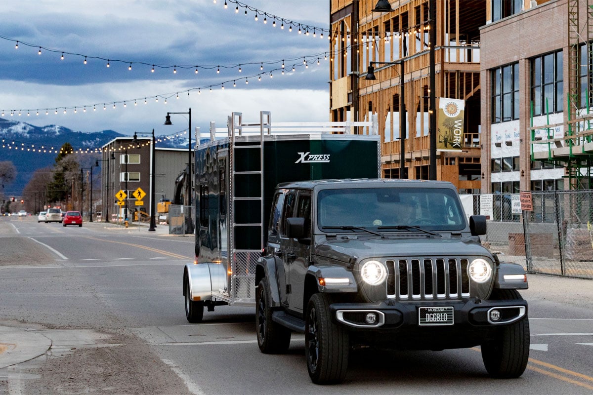 Gray Jeep Hauling Enclosed Cargo 5/6 Wide Trailer In City