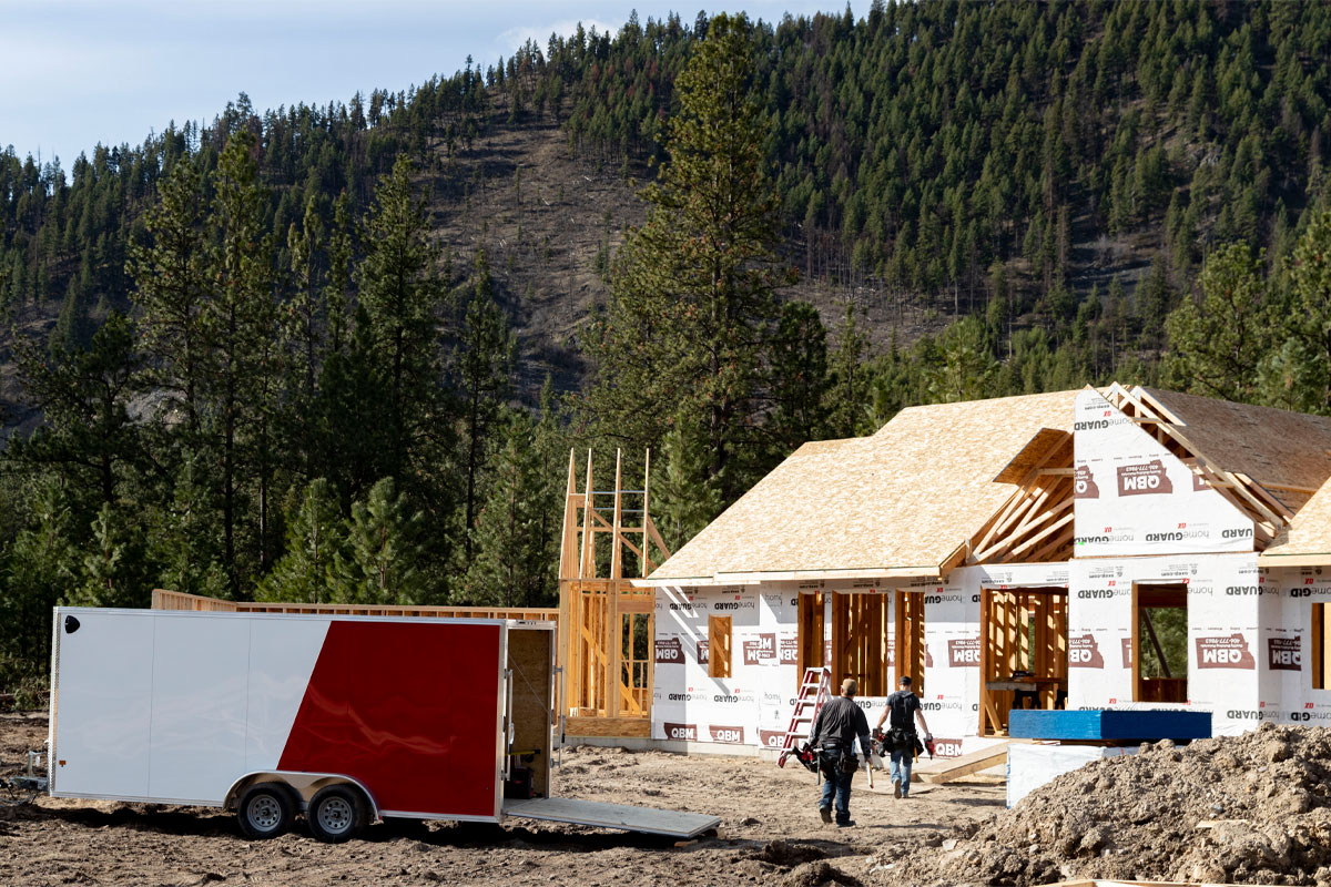 White Truck Hauling Xpress White Enclosed Cargo 8.5 Wide Trailer At Construction Site